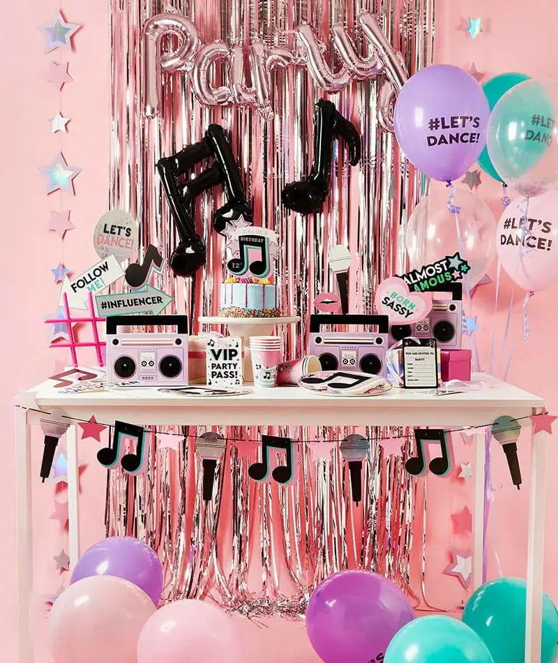 Music-themed birthday party display with balloons, a birthday cake, speaker decorations, musical note balloons, and pink party décor. Music-themed birthday party display with balloons, a birthday cake, speaker decorations, musical note balloons, and pink party décor.